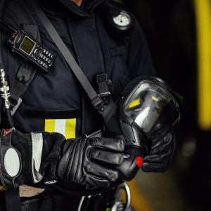 Rescue firefighter in safe helmet and uniform standing by car