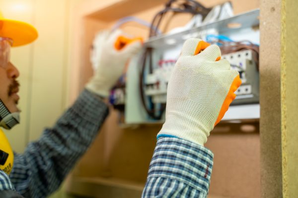 Electrician at work at House,Electrician repairing electrical box with pliers in corridor of a residential electrical system.